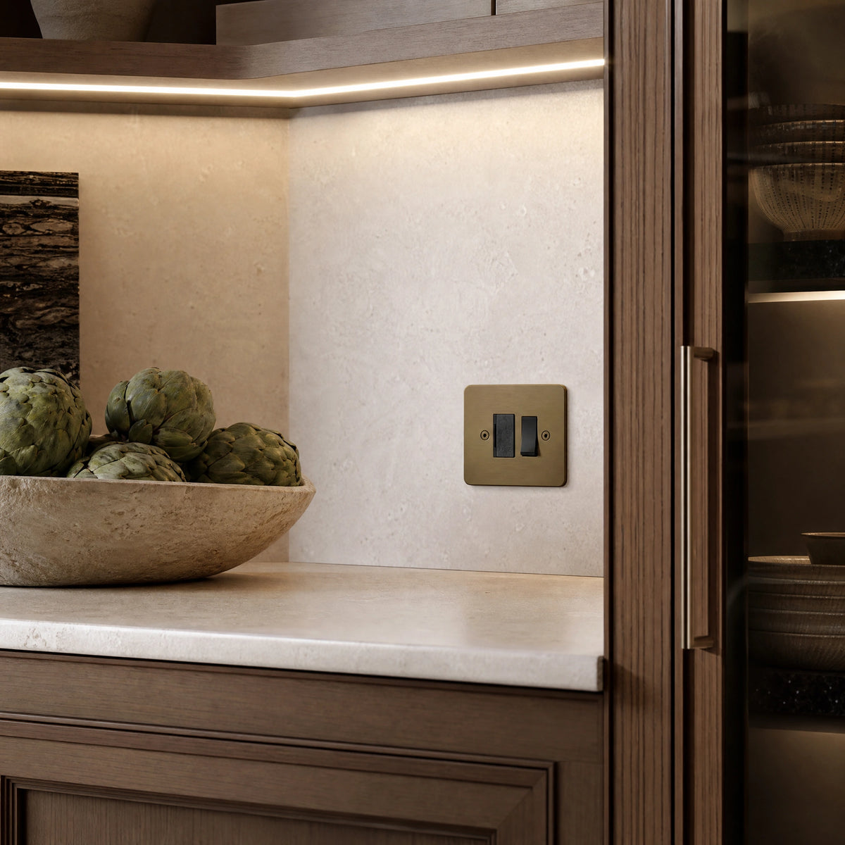 Luxury antique brass fused spur installed within discreet below-cabinet utility or kitchen appliance zone in a high-end residence in a UHNW interior by VORELLI®.