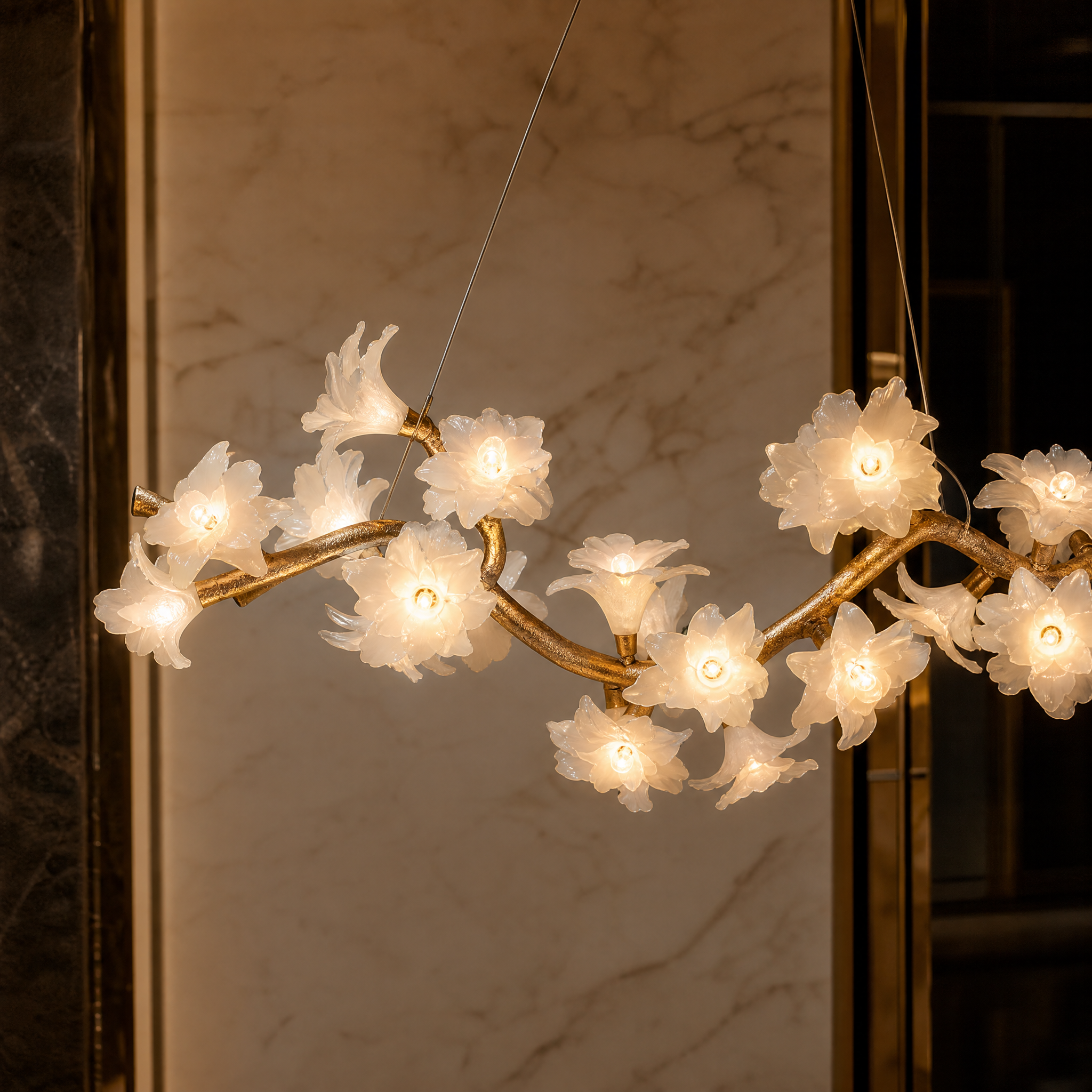Macro shot of the sculptural branch frame and delicate glass floral blossoms of the VORELLI Gardenia Chandelier, emphasizing quiet luxury.