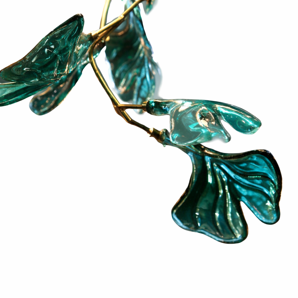 Close-up of sculptural green glass leaves and warm LED lighting forming an artistic luxury chandelier