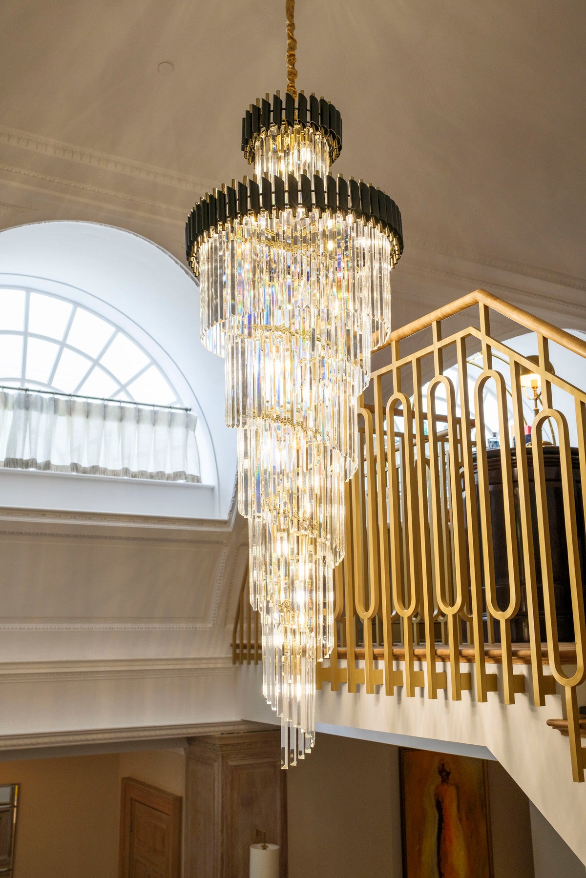 Luxury crystal staircase chandelier by VORELLI® cascading through a grand entrance foyer with gold balustrade
