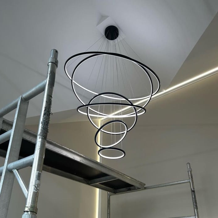 VORELLI Marcello spiral LED ring chandelier positioned within a contemporary staircase void