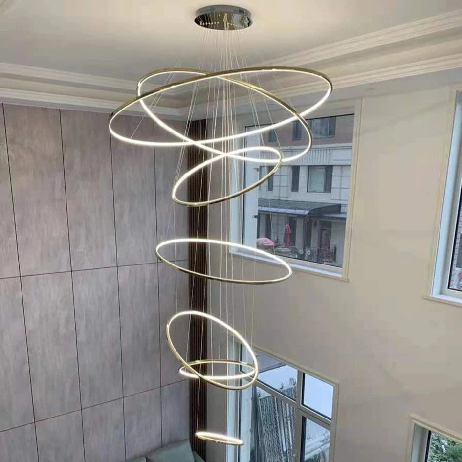 Spiral arrangement of illuminated LED rings cascading through a staircase void in the VORELLI Marcello chandelier