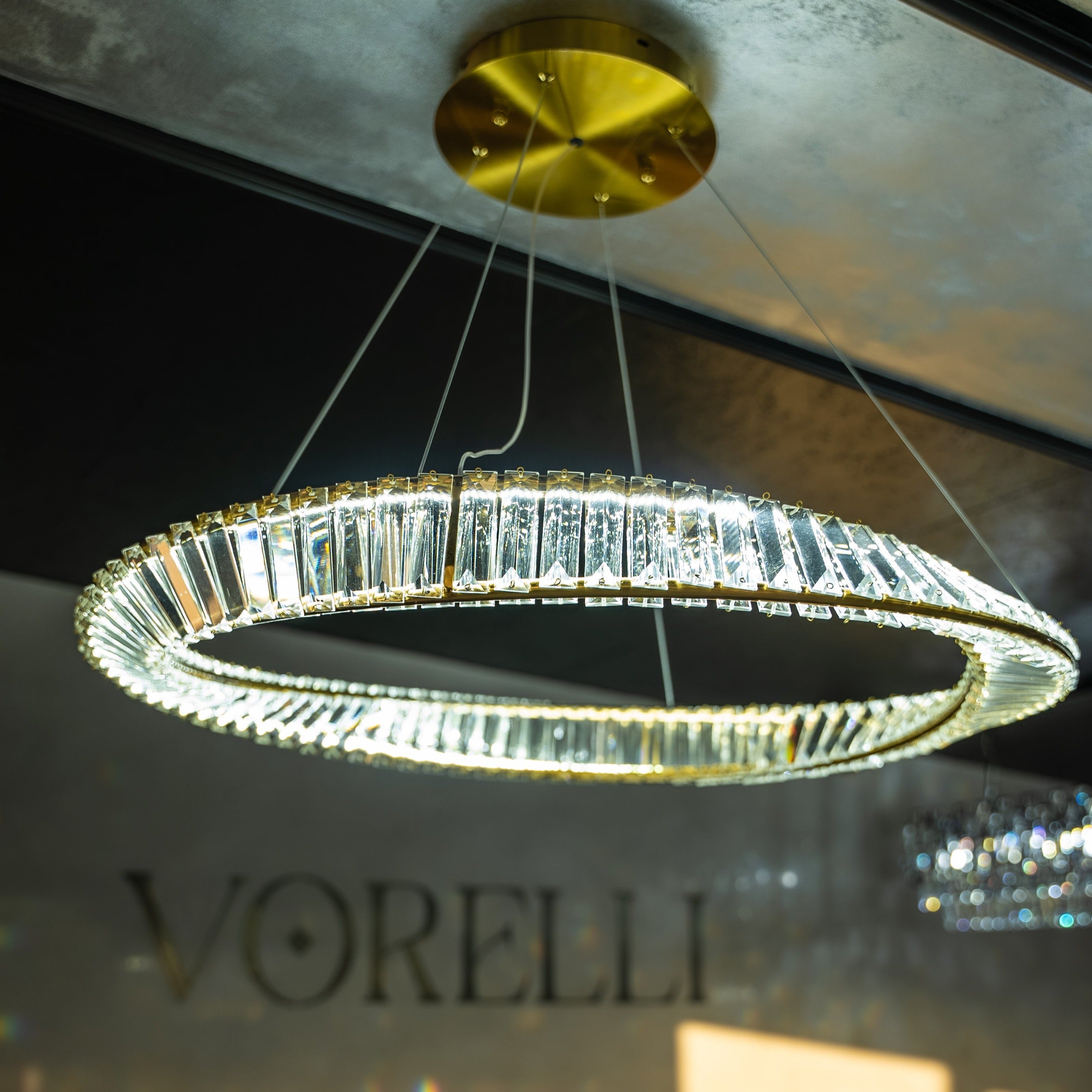 Close-up of the twisted crystal bar ring and gold ceiling plate on the VORELLI Melia circular chandelier