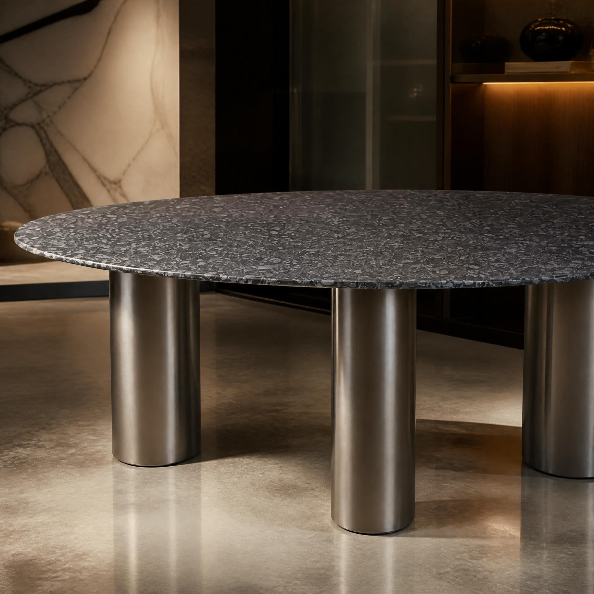 A detailed closeup of the VORELLI Nisha dining table top, highlighting the unique fossilised sea shells embedded within the honed Fossil Black marble slab and the brushed stainless steel leg.