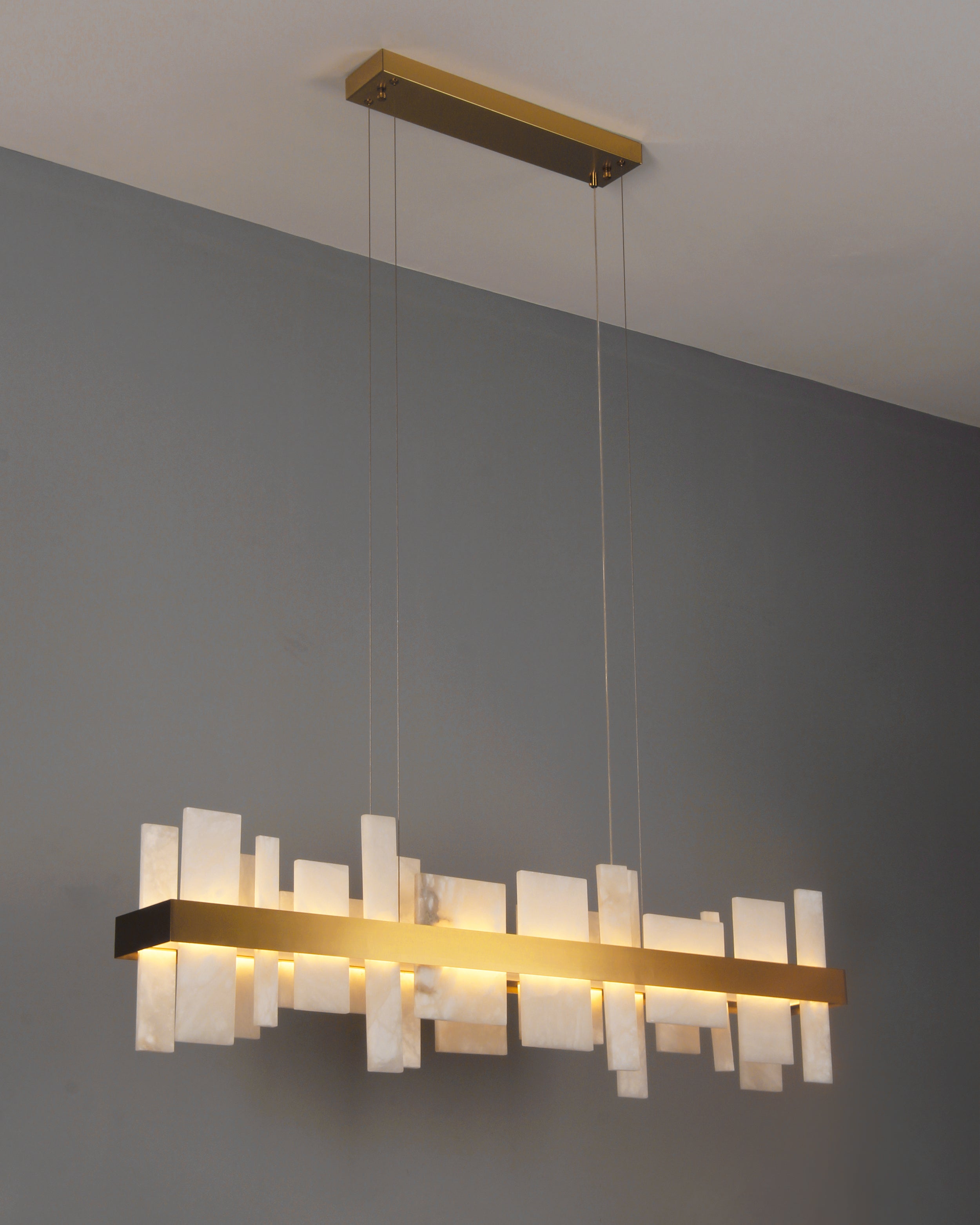 Detailed side view of VORELLI® Niva marble rectangular chandelier showing layered stone panels and warm illumination