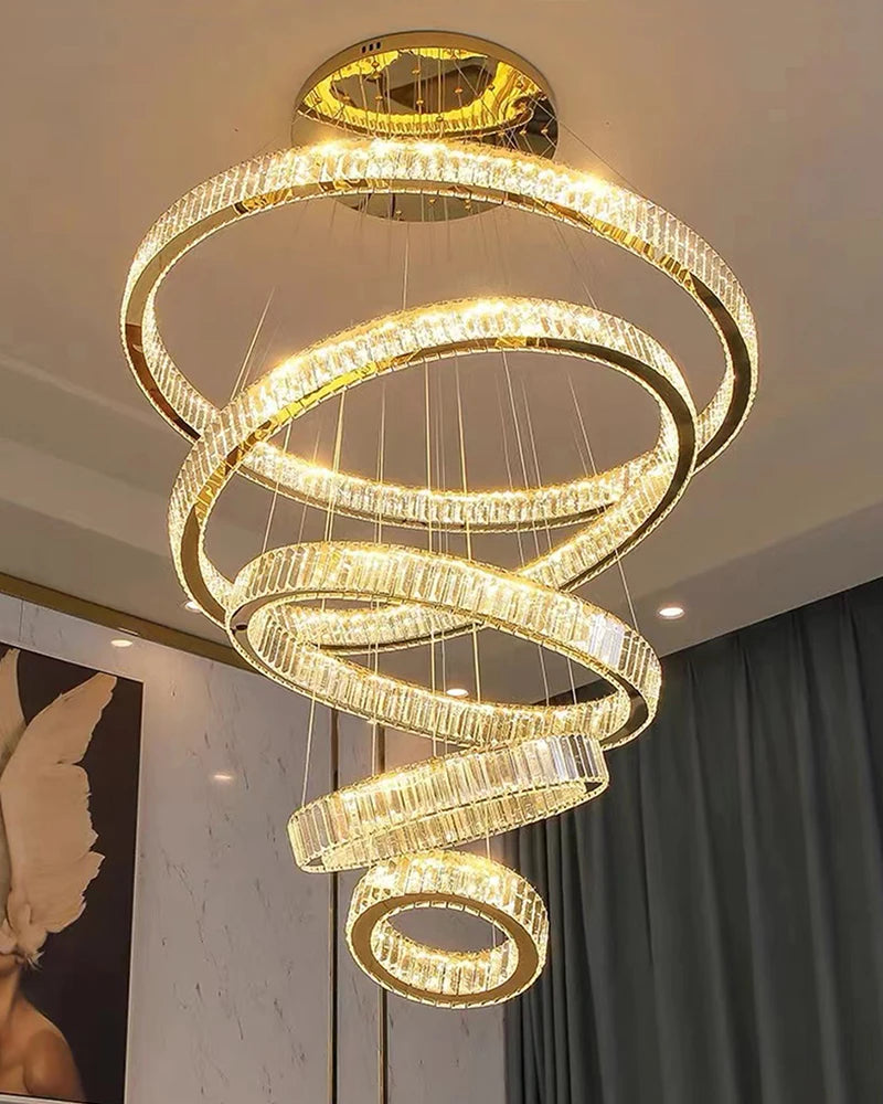VORELLI® Oia spiral ring chandelier suspended in a double-height staircase creating elegant luxury ambient lighting