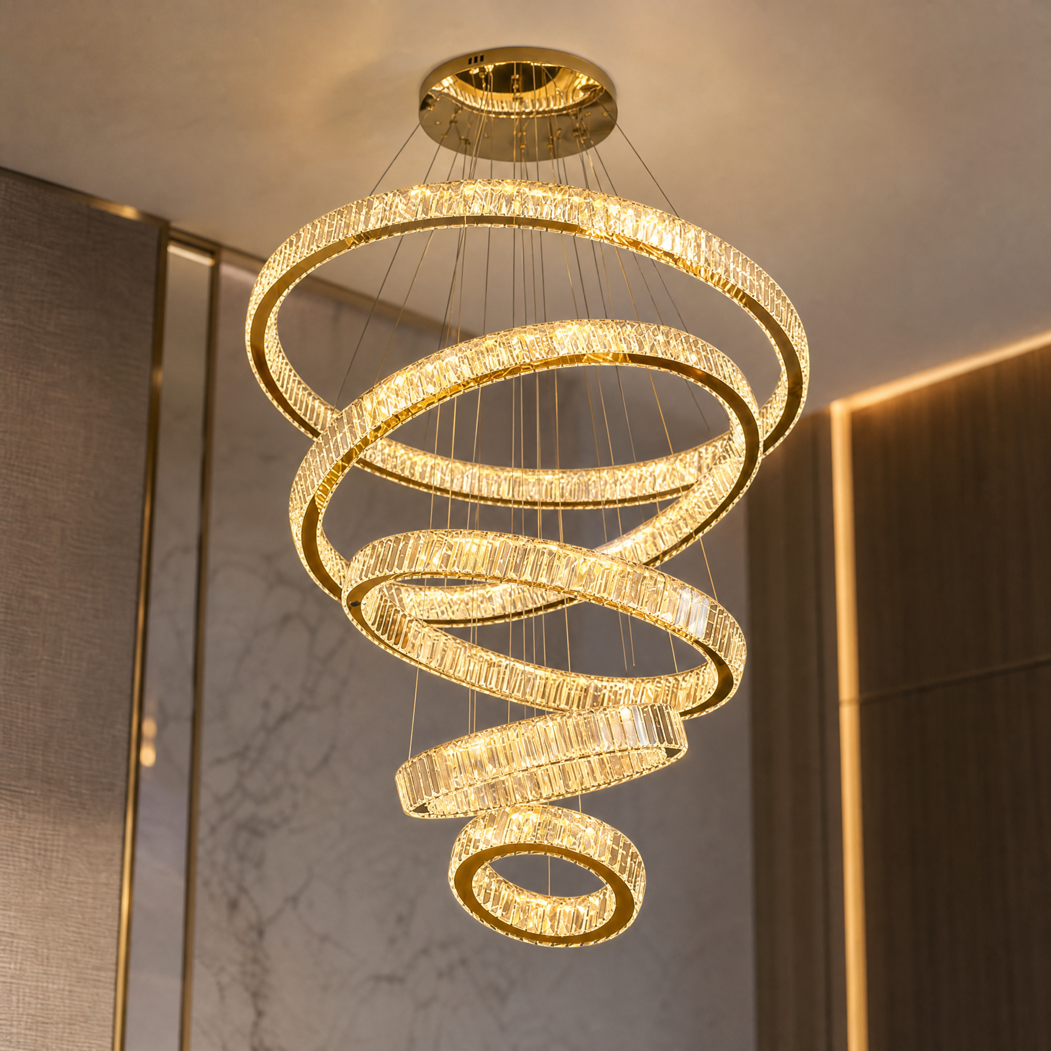 A detailed closeup of the VORELLI Oia Staircase Chandelier, highlighting the precision-cut crystal bars encircling a polished stainless steel interior ring.