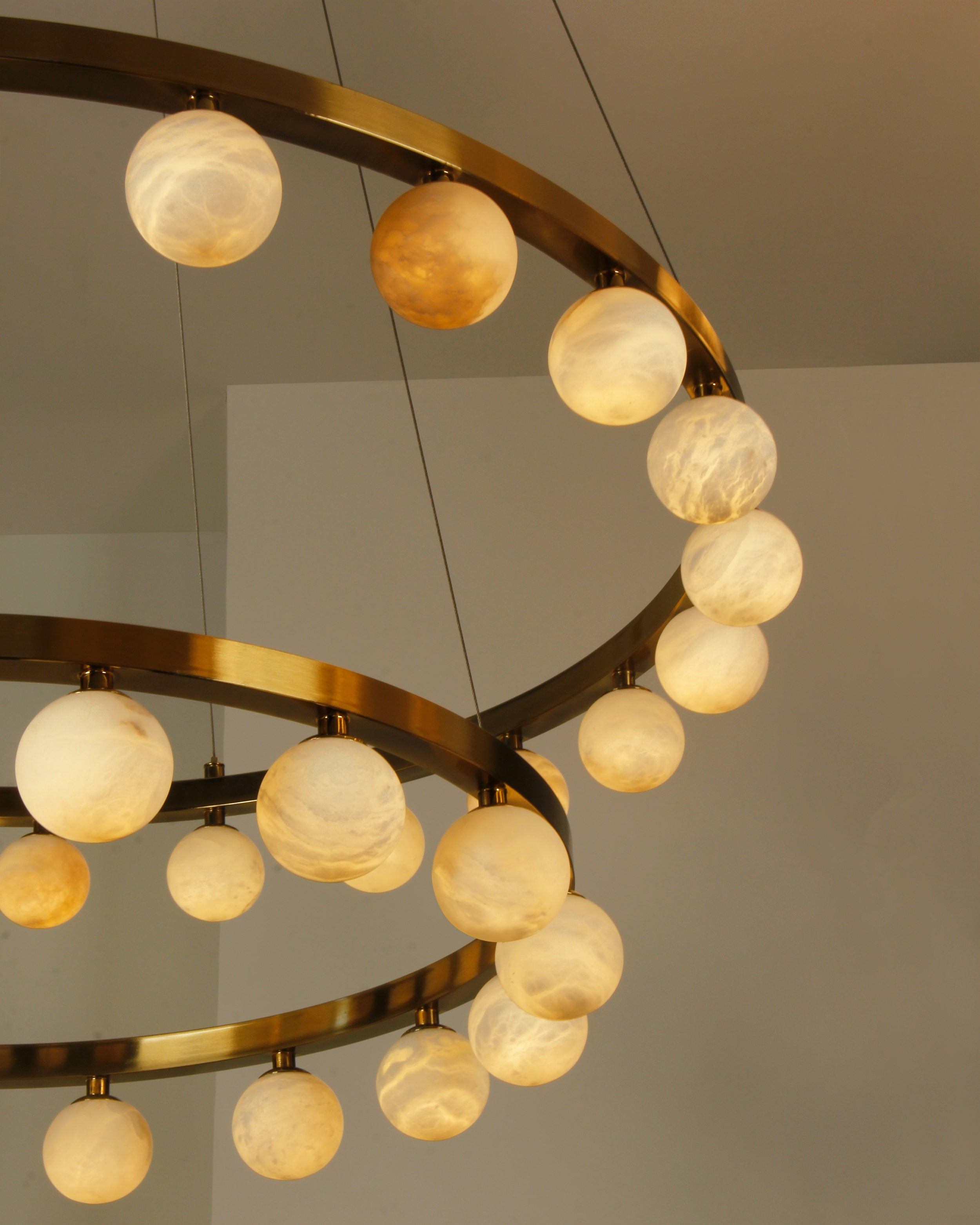 Close up of illuminated marble spheres arranged along circular ring on VORELLI® Orbit chandelier