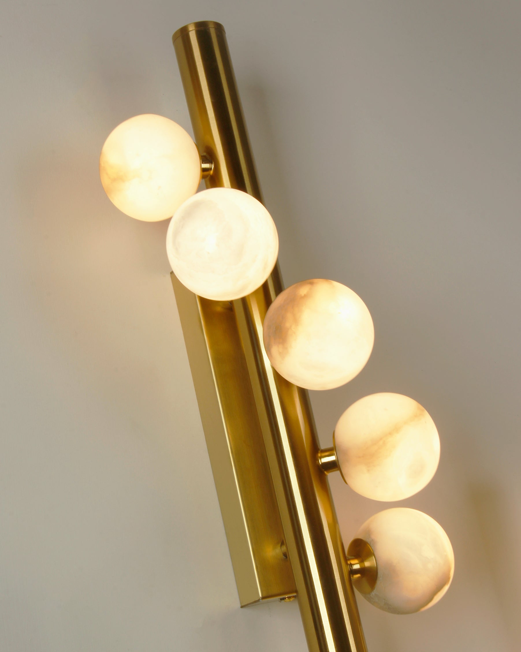 Detailed angled view of VORELLI® Orbit marble globe wall light highlighting vertical frame and sphere placement