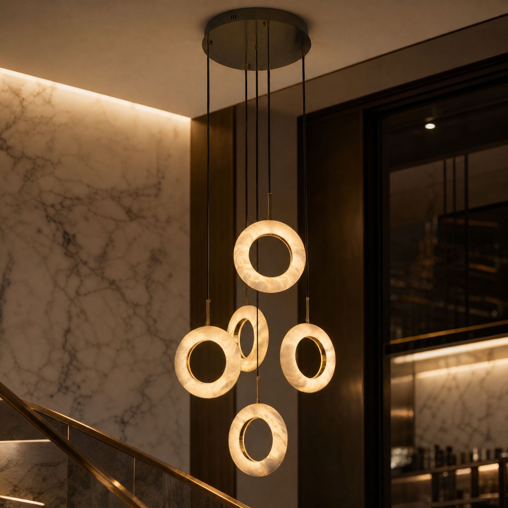 Close-up detailed view of the organic texture and glowing marble finish on the VORELLI Pietra staircase pendant light rings.