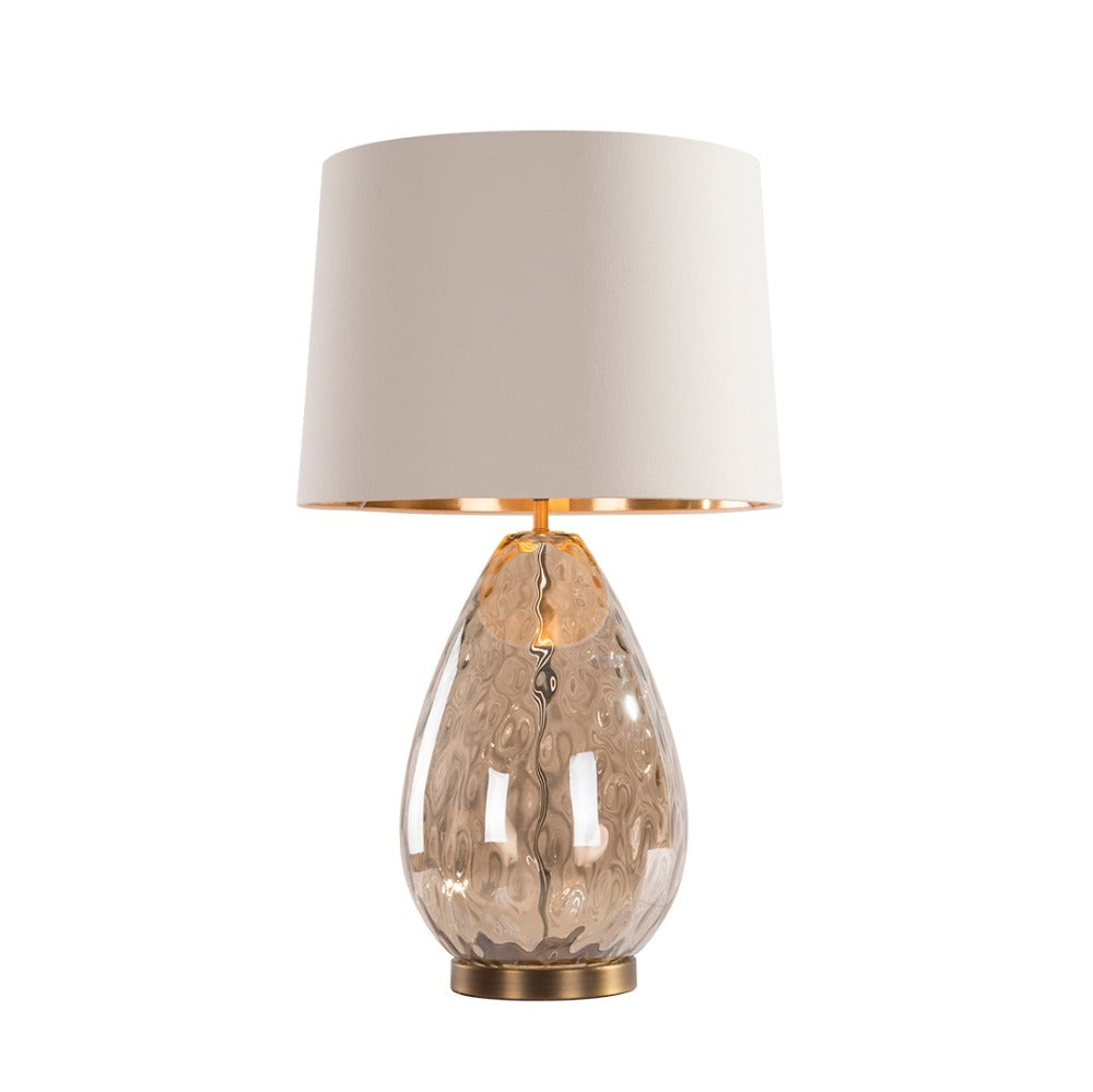 Riom glass table lamp featuring sculpted amber toned glass base and fabric shade in elegant modern design on white background