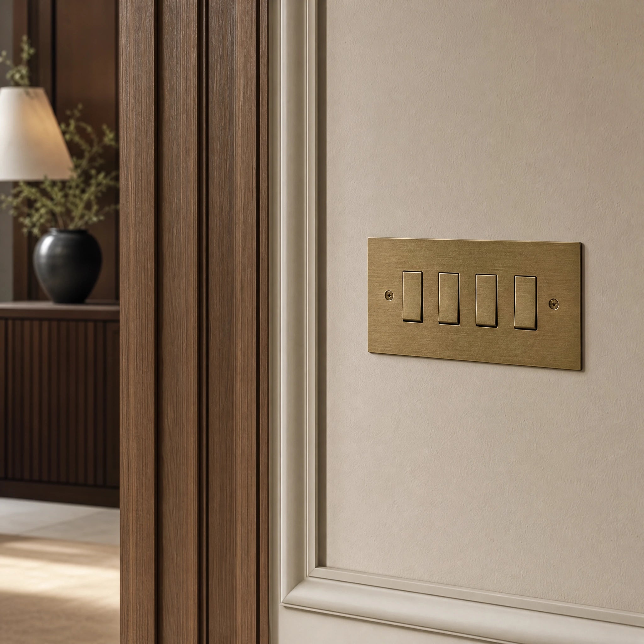 Close-up of a luxury antique brass rocker switch installed within feature wall beside an elegant doorway with refined timber panelling by VORELLI®.