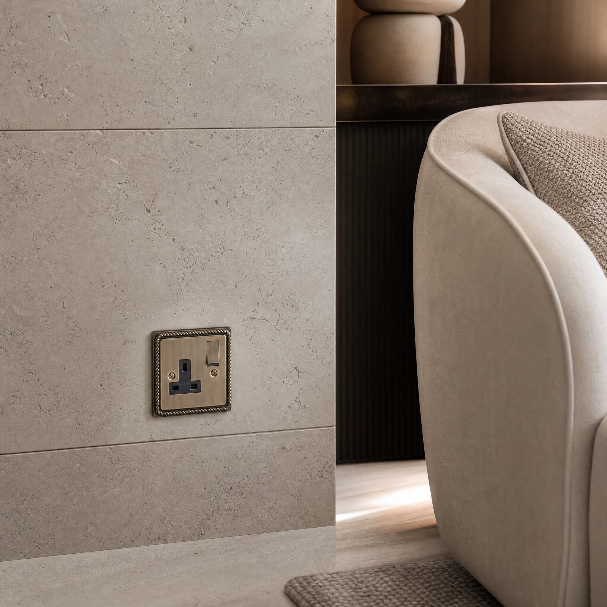 Luxury antique brass single socket installed within bespoke bedside joinery or stone wall beside a luxury seating area in a UHNW interior by VORELLI®.