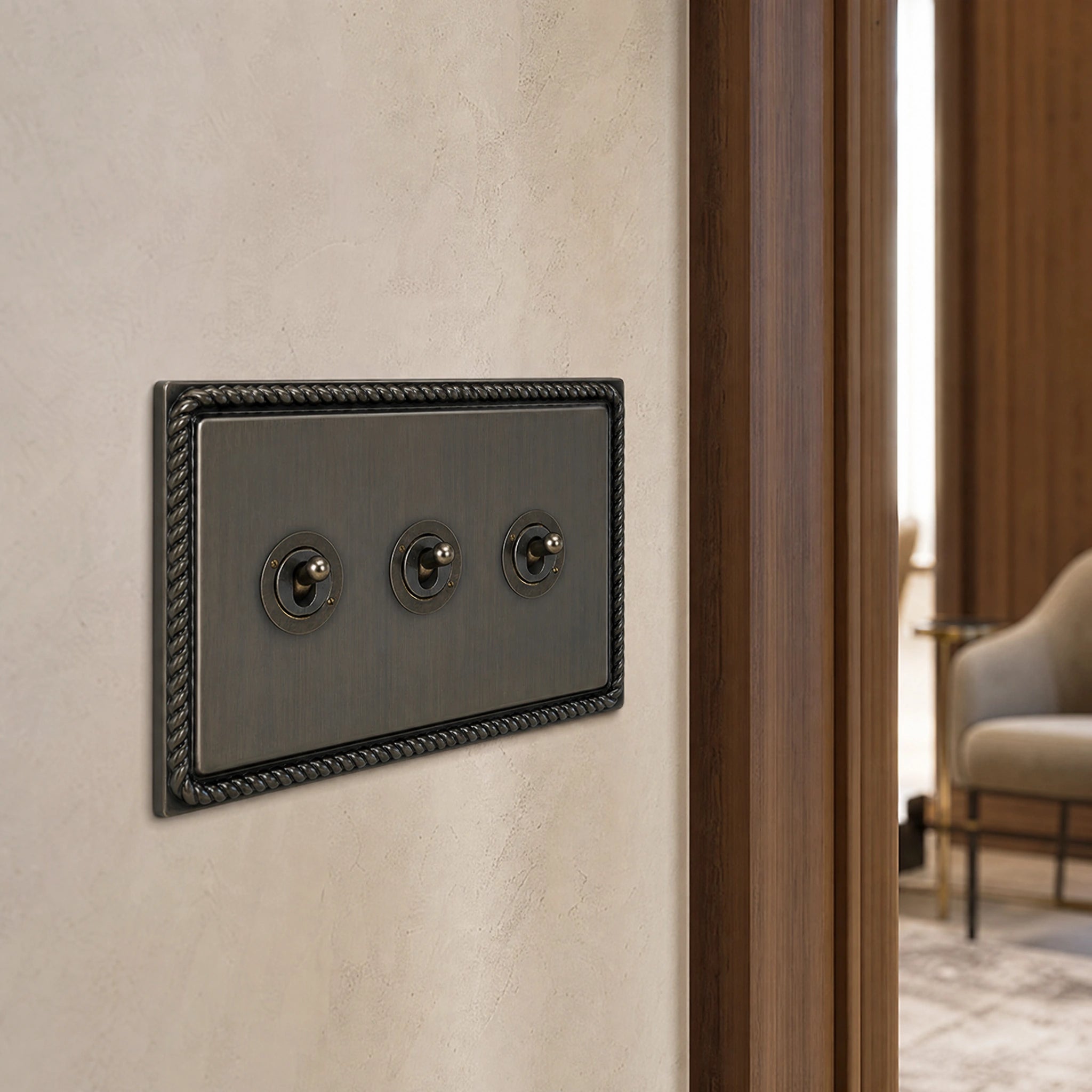 Close-up of a luxury antique brass toggle switch installed within feature wall beside an elegant doorway with refined timber panelling by VORELLI®.