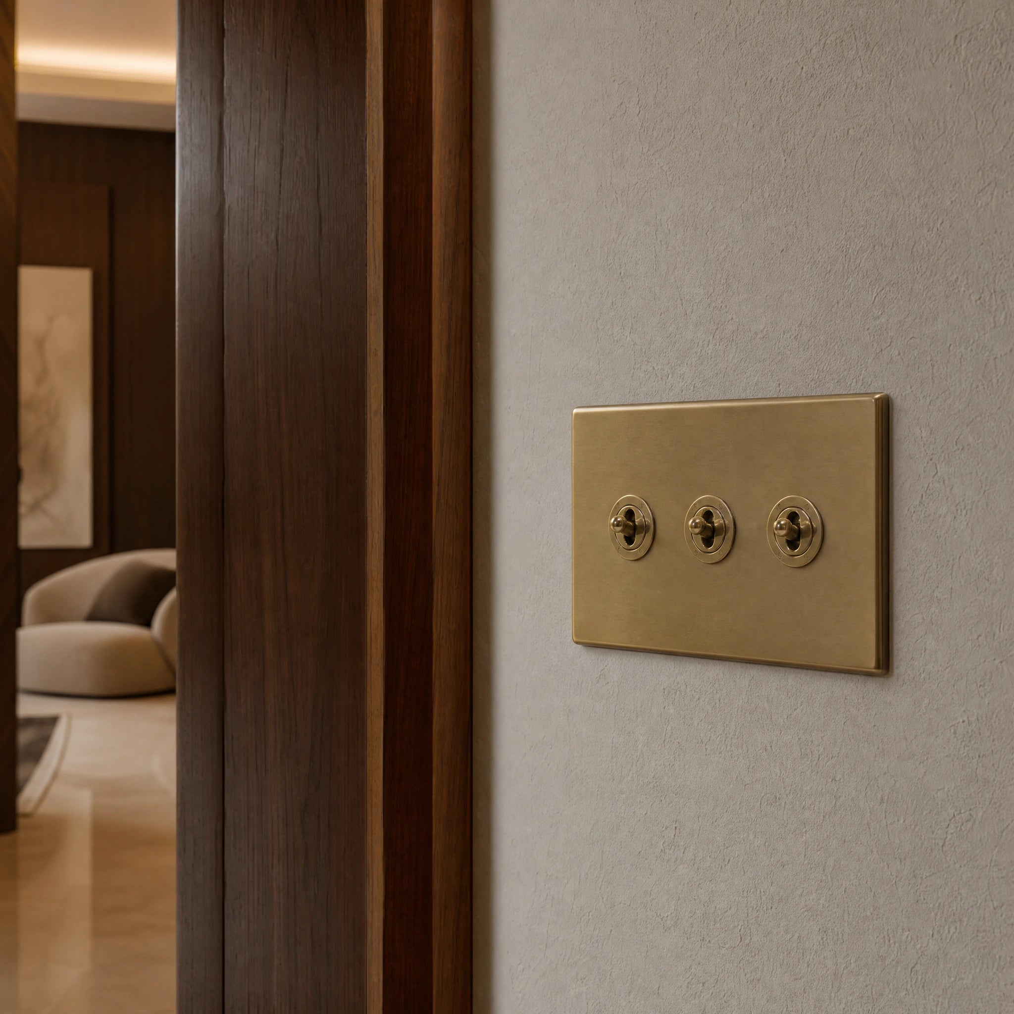 Close-up of a luxury antique brass toggle switch installed within feature wall beside an elegant doorway with refined timber panelling by VORELLI®.