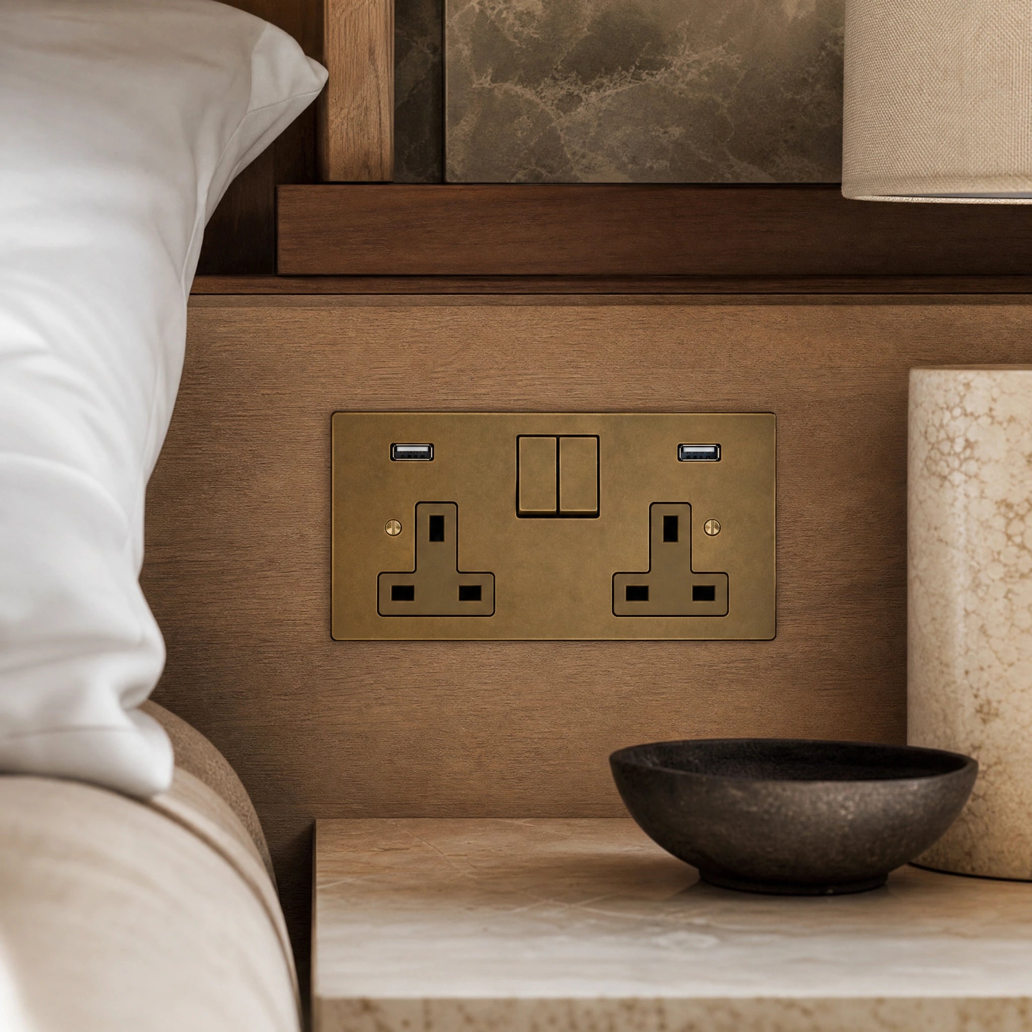 Close-up of a luxury antique brass usb socket installed within bespoke bedside joinery in a luxury bedroom suite by VORELLI®.