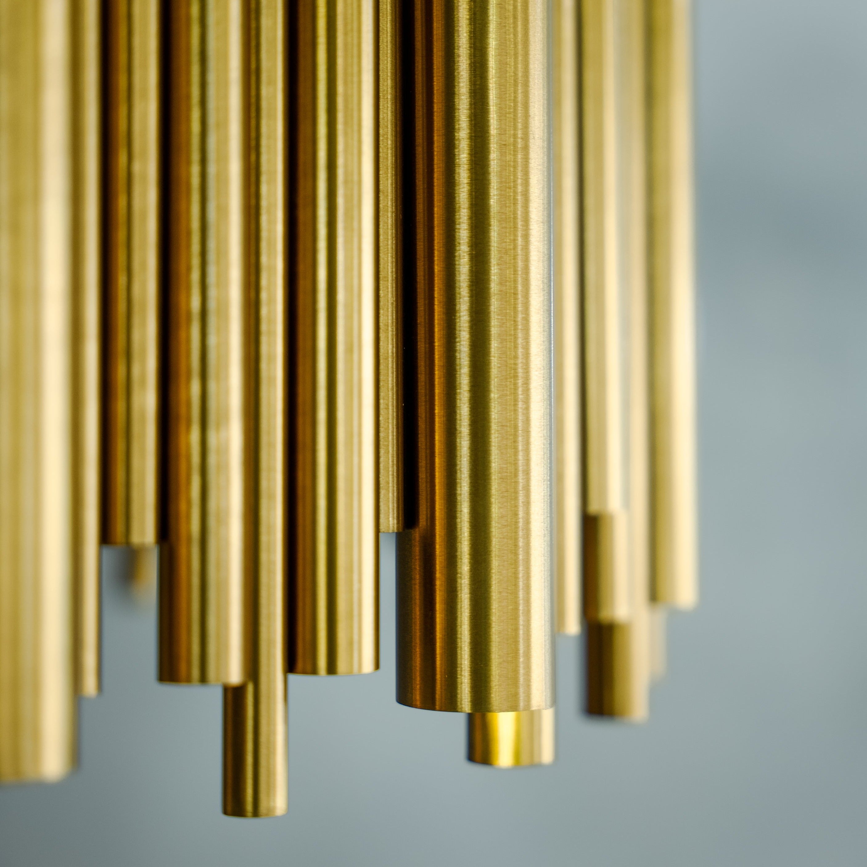 Close-up of hanging cylindrical tubes on circular chandelier creating layered modern luxury lighting effect