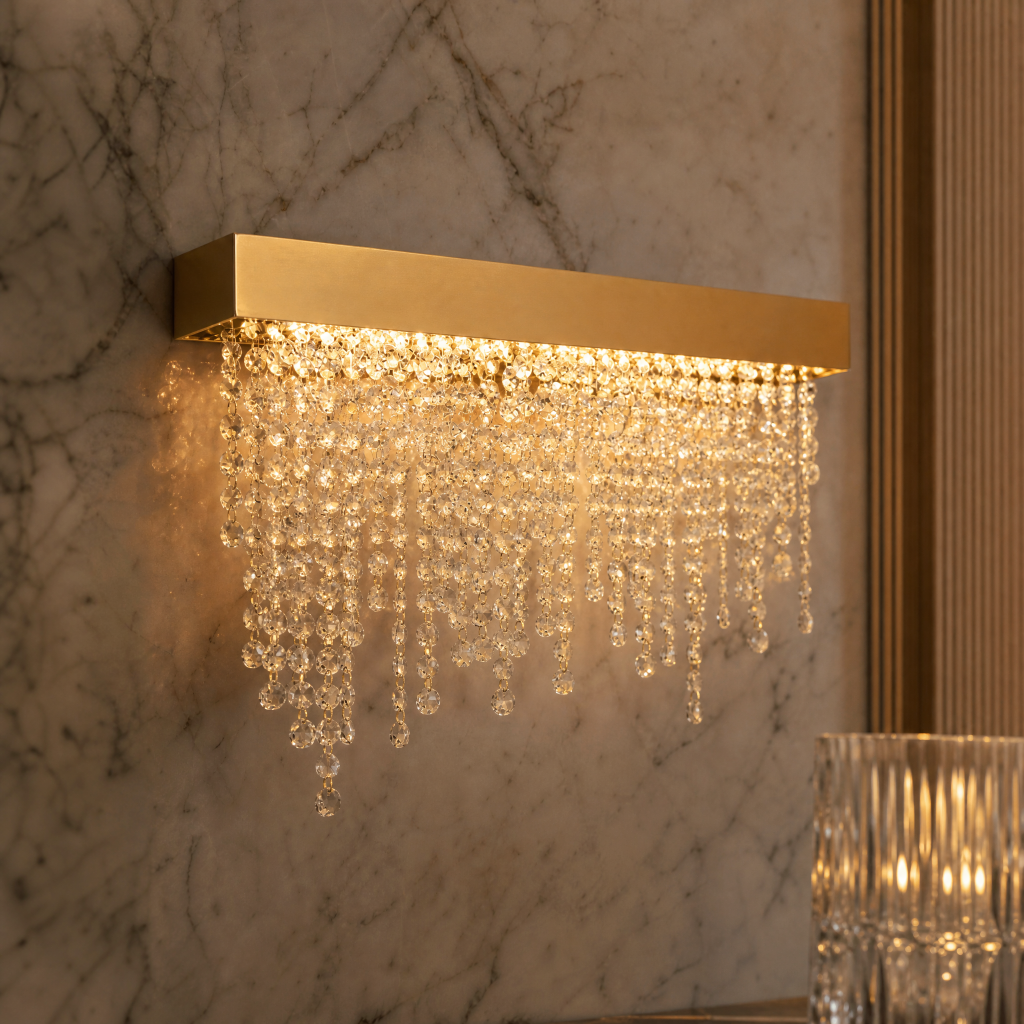 A detailed closeup of the VORELLI Westminster Wall Light, showcasing the brilliant crystal chain draped over a sleek stainless steel frame.