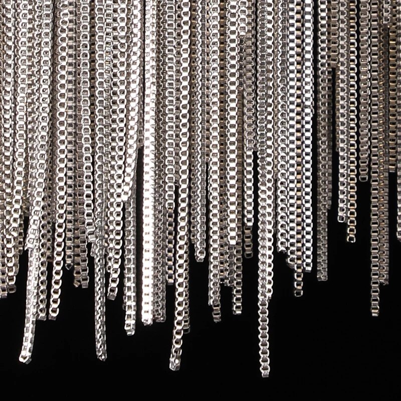 Close-up detail of the Adlington wall light showcasing cascading diamond cut metal chains that create a refined, contemporary luxury lighting effect.