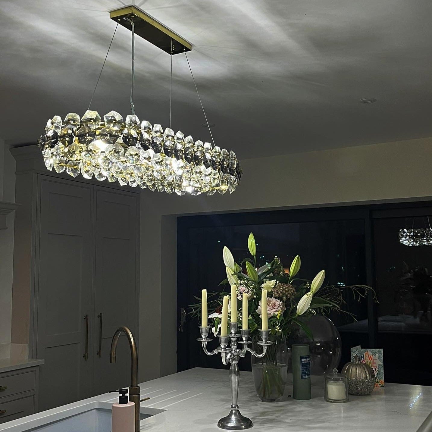 Astoria chandelier in a hallway or open space, emitting soft ambient light with a rectangular form.