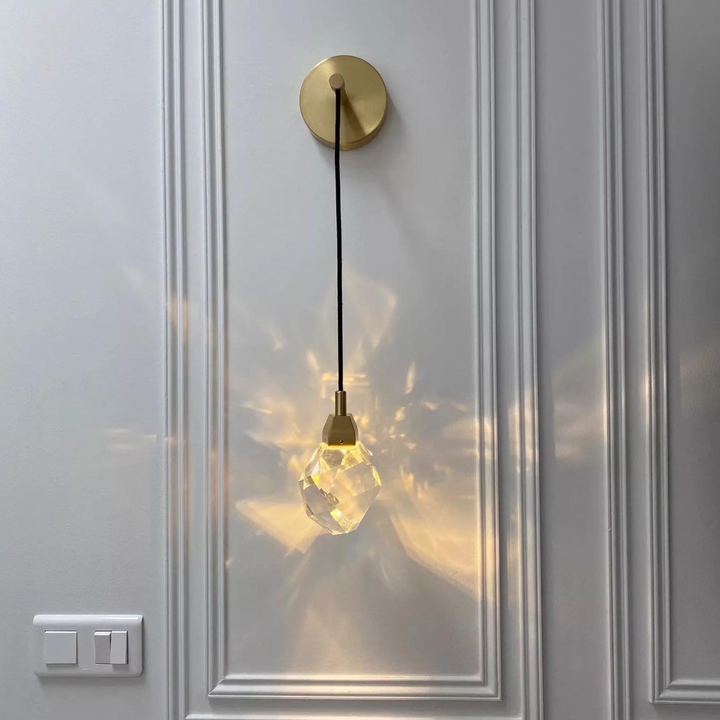 Runtz Wall Light II modern crystal drop wall sconce installed on decorative panel wall creating refined ambient glow