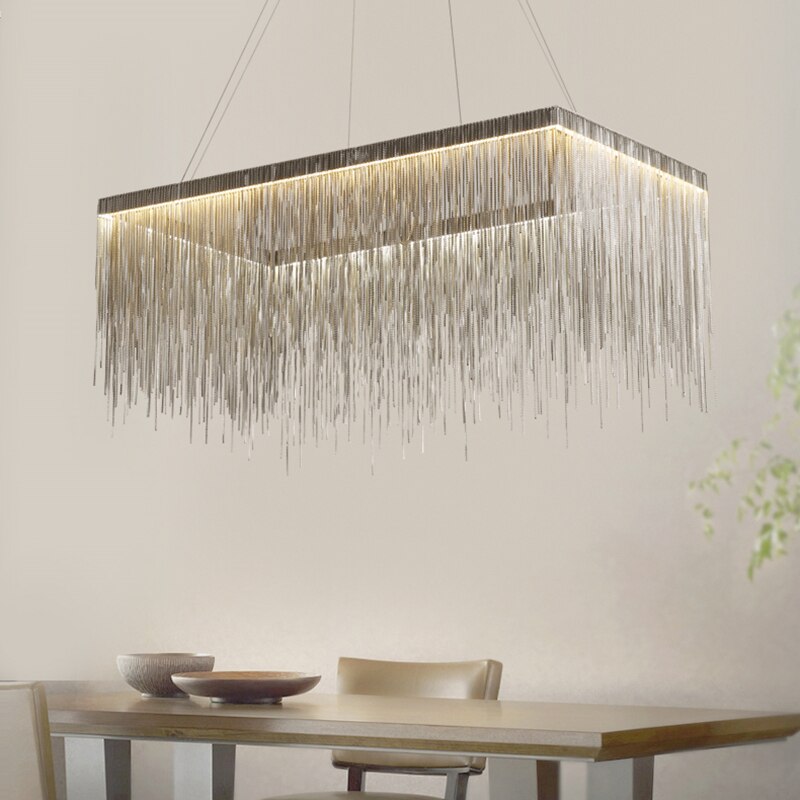 VORELLI® Adlington Rectangular Chandelier suspended above a modern dining table with light wood chairs