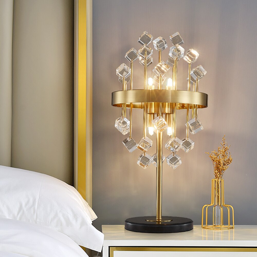 Alytus Table Lamp with clear crystal spheres and gold sculptural frame styled on a luxury bedside table.
