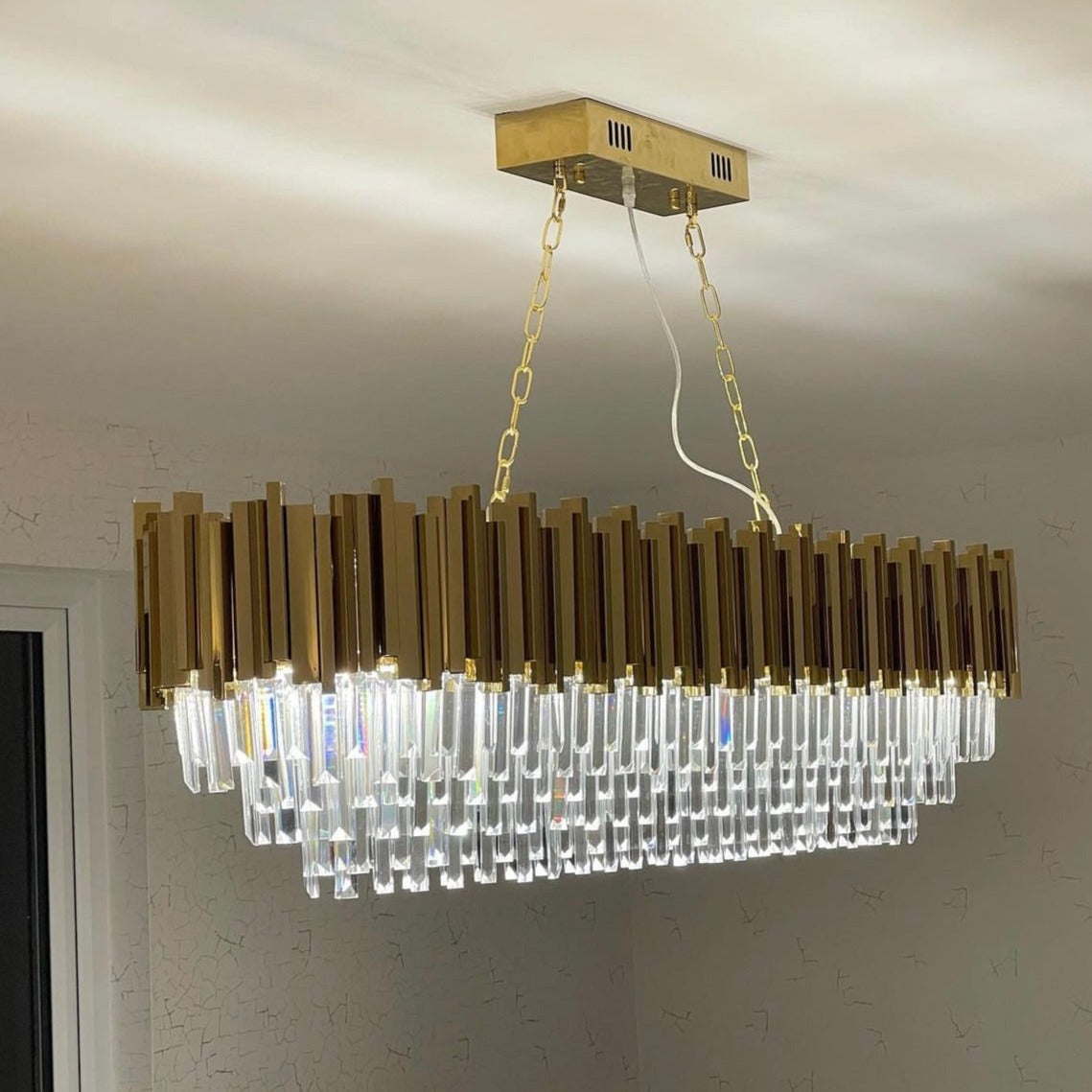 Boeotia Rectangular Chandelier mounted to the ceiling with gold tubing and cascading crystal elements.