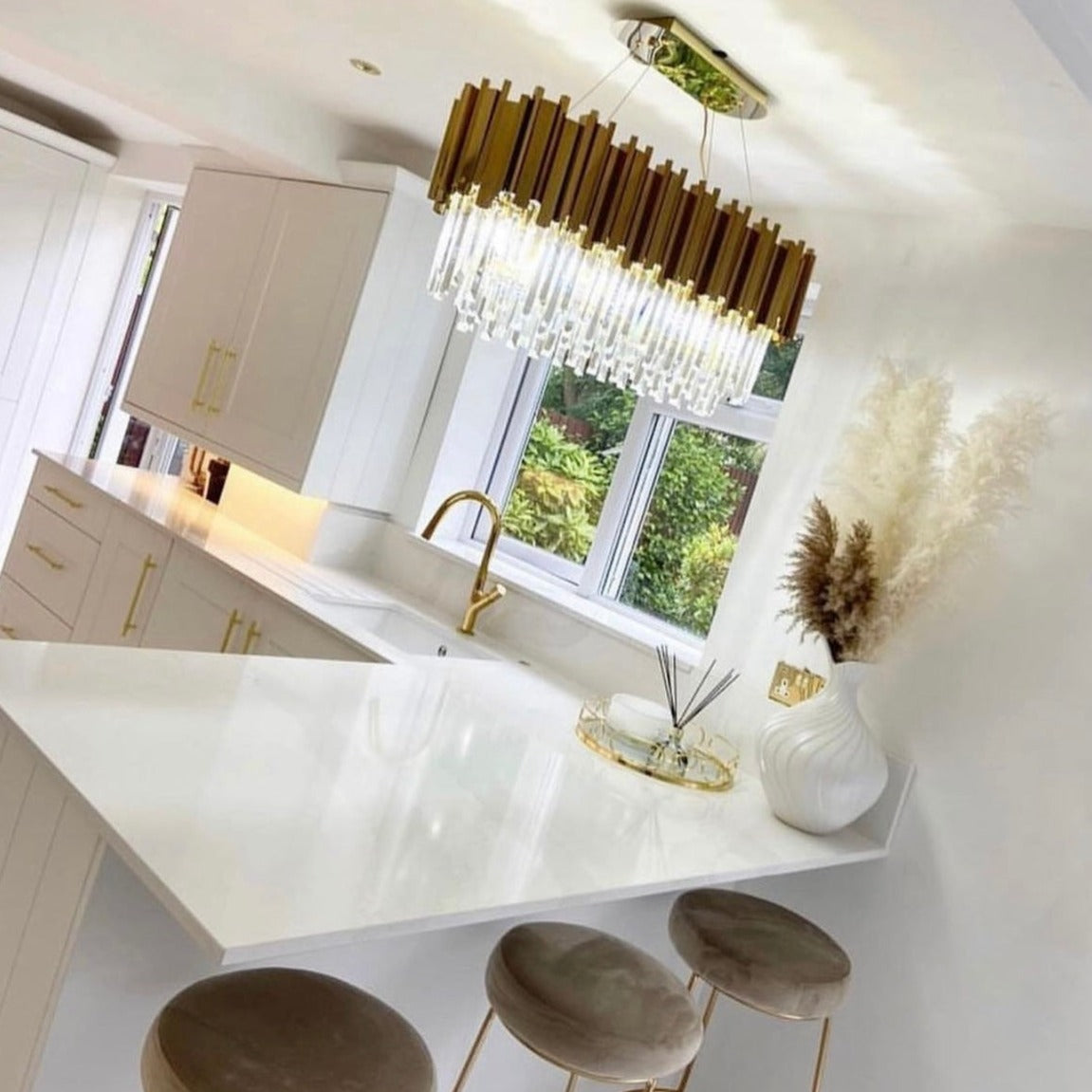 Illuminated crystal bars of the Boeotia Rectangular Chandelier displayed in a bright contemporary space.