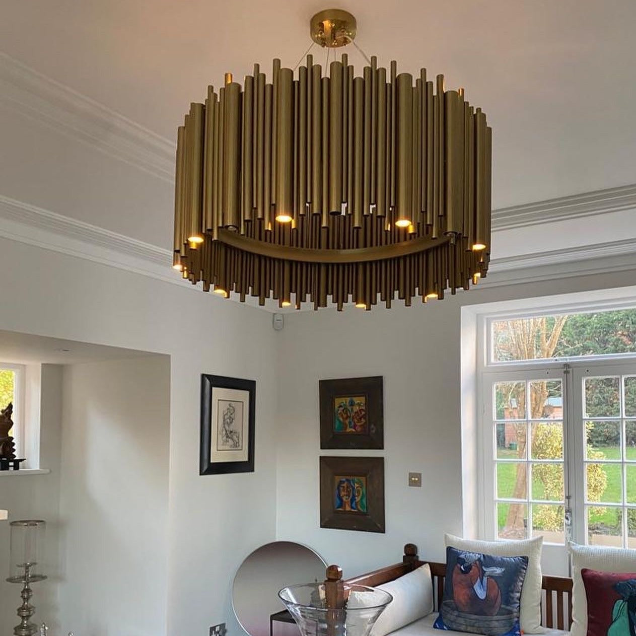 Modern circular chandelier with cylindrical tubes creating ambient lighting in luxury interior