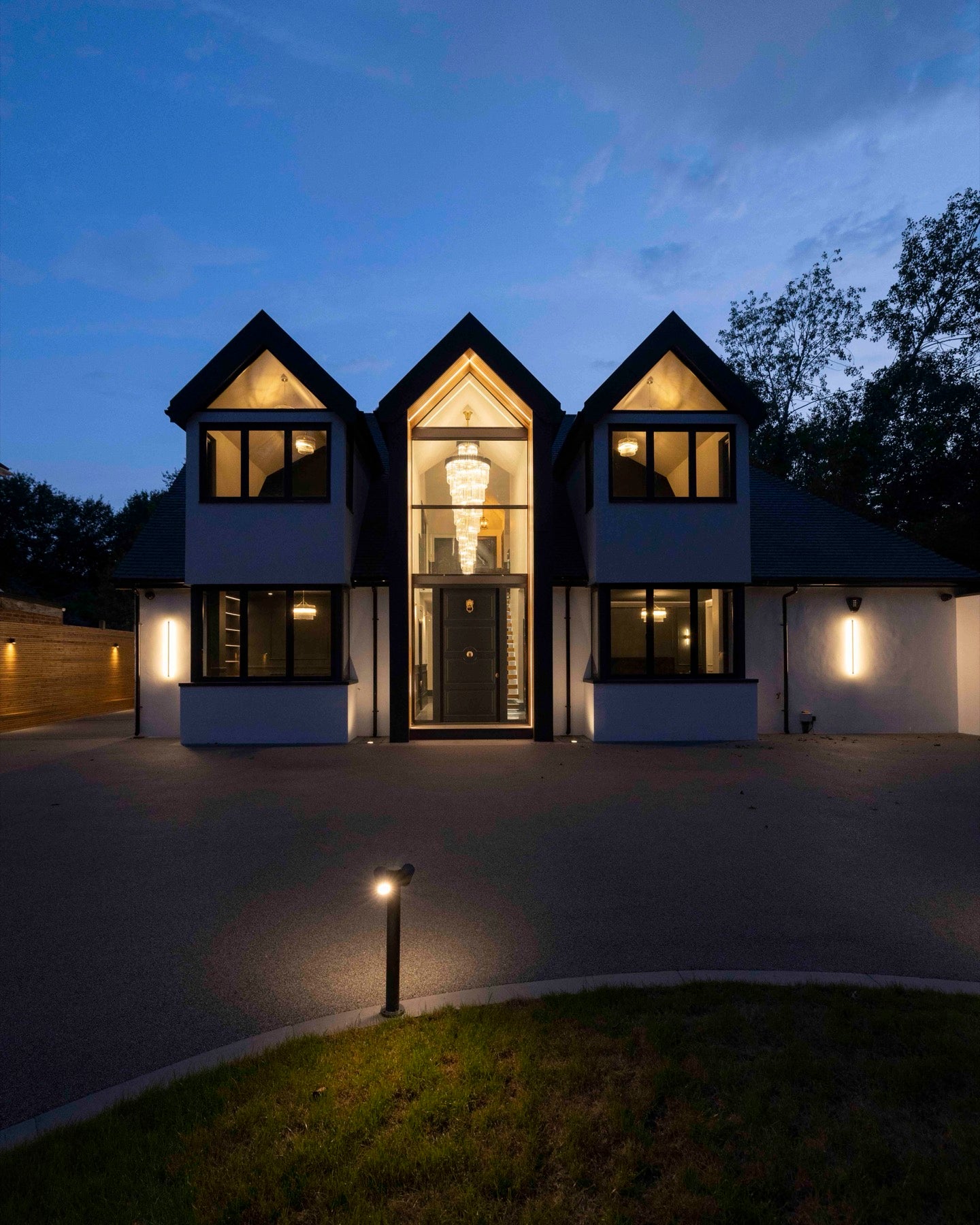 Evening exterior of a Purley private residence with entrance chandelier and wall lighting